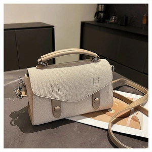 Detail of cream canvas handbag with tan leather trim and dual cylinder buckles