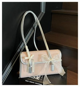 Detail of pink lace bow shoulder bag with silver leather handles on a black book