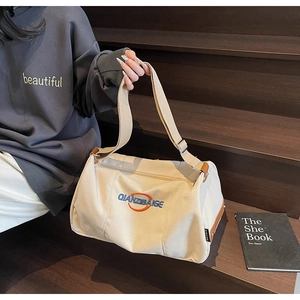Détail du sac Boston en toile beige avec garniture en cuir brun et logo brodé de marque
