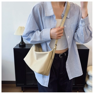 Detailed view of beige PU leather crossbody bag with adjustable strap on a model
