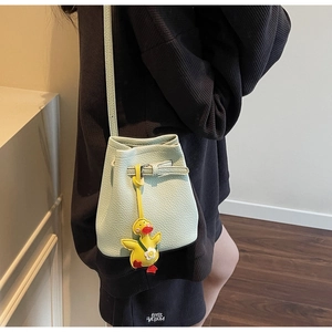 Detail of mint green lychee textured bucket bag featuring a cute yellow duck pendant charm