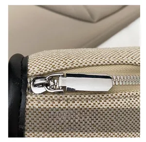 Detail of smooth silver zipper and textured beige canvas with black leather trim