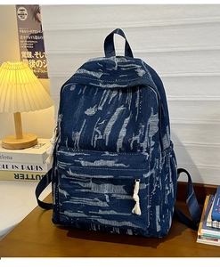 Detailed view of dark blue denim backpack featuring tie-dye patterns and rope zipper pulls