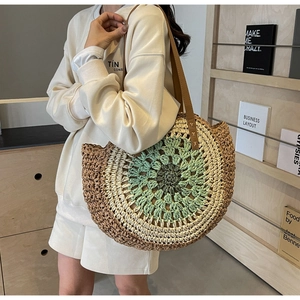 Detail of round straw beach bag featuring geometric pattern and leather shoulder straps