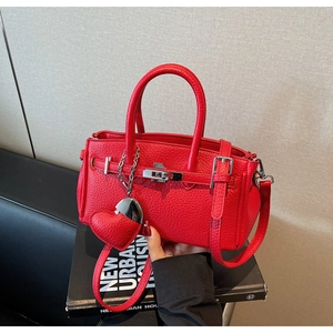 Dettaglio della borsa rossa in pelle martellata con ciondolo a cuore e fibbia metallica