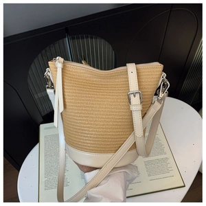 Detail of the woven straw texture and cream leather trim on the casual bucket bag