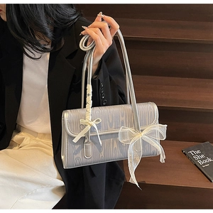 Close-up of silver rectangular bag with wood grain texture and white lace bow details