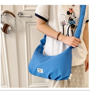 Detail der marineblauen Falten-Tasche mit Stoffaufnäher und strukturiertem Schultergurt