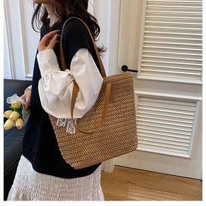 Detail of handwoven straw tote bag with brown leather handles and white lace bow detail