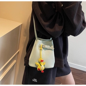 Detail showing light green lychee texture bucket bag with a cute yellow duck plush charm