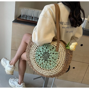 Detail of hand-woven round paper straw beach bag with colored patterns and leather straps