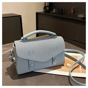 Detail of light blue crossbody bag featuring twill fabric texture and silver hardware