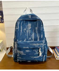 Detailed macro of distressed denim backpack with frayed holes and white tassel zipper