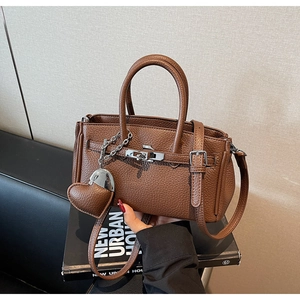Dettaglio borsa in pelle martellata marrone scuro con chiusura argento e ciondolo a cuore