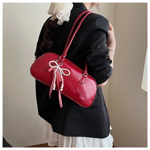 Dettaglio borsa in pelle rossa con fiocco di perle e nastro a quadretti rossi e bianchi