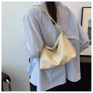 Detail of adjustable strap and soft beige hobo bag on a model wearing striped shirt