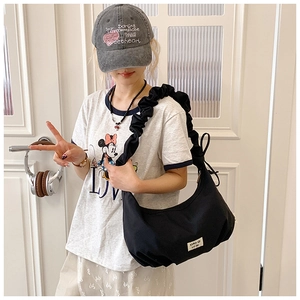 Detail einer schwarzen Hobo-Tasche mit plissiertem Schultergurt an einem Model