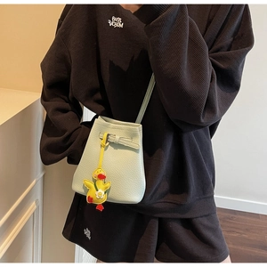 Detail of mint green bucket bag featuring lychee texture and cute duck charm on model