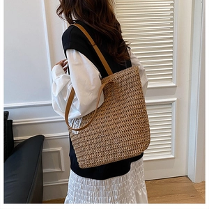 Detail of the natural woven straw tote with brown leather straps and white lace trim