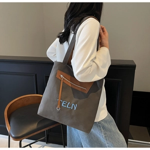 Détail du cabas en toile grise avec poche en cuir marron et broderie TELN bleue