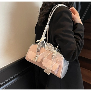 Close-up of pink underarm bag featuring side pockets and silver heart charm on model
