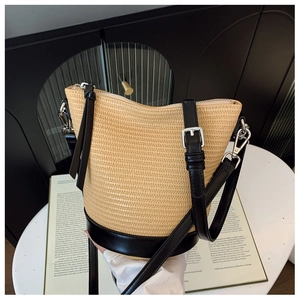 Close-up of woven straw bucket bag with black leather trim and silver buckle detailing