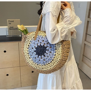 Detail of bohemian round straw beach bag with gradient blue woven pattern and leather strap