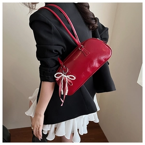 Borsa a spalla rossa con dettaglio di perle e fiocco indossata dalla modella