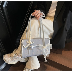 Detail of silver-grey bow shoulder bag with textured metallic finish and mesh ribbon