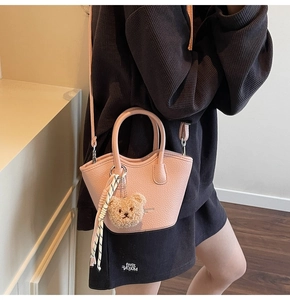 Détail du mini sac seau rose avec texture cuir et adorable breloque ours en peluche