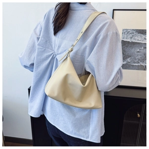 Minimalist beige leather tote bag with adjustable buckle strap on casual model