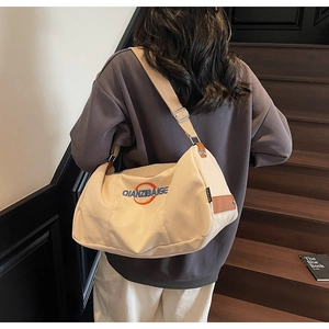 Détail de la large bandoulière réglable en toile et de l'accent en cuir sur le sac beige