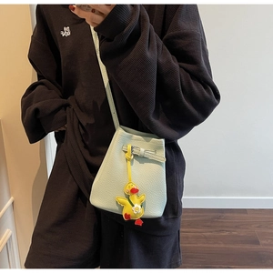 Detail of mint green bucket bag featuring a yellow duck charm and leather strap