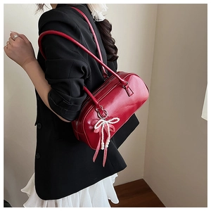 Dettaglio della borsa Boston bordeaux con pendente a fiocco e finitura in pelle lucida