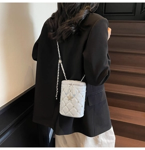 Sac seau matelassé avec détail d'étoile porté par un mannequin dans un escalier doux