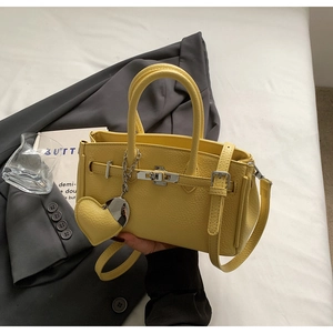 Dettaglio della borsa gialla in pelle con chiusura girevole argento e pendente a cuore