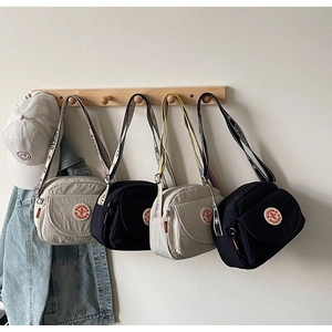 Detail of jacquard wide straps on square crossbody bags in black and cream beige colors