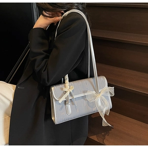 Detail of silver silk texture shoulder bag with white lace bow on elegant grey fabric