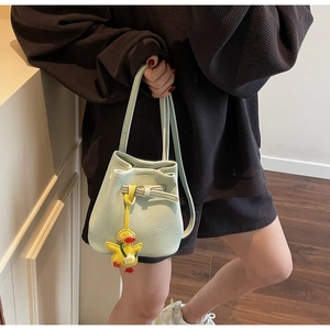 Detail of mint green pebble leather bucket bag with a cute yellow duck pendant accessory