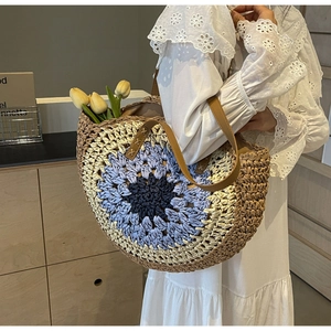 Detail of multi-color woven straw tote bag with brown leather handles and chic tulip decor