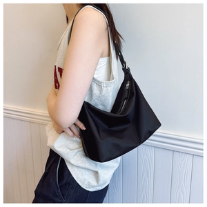 Side view of black nylon hobo bag with silver zipper and adjustable strap on a model