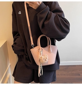 Vue détaillée du sac seau rose en cuir grainé avec pendentif ours et bandoulière
