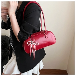 Dettaglio borsa boston in pelle rossa con ciondolo elegante in perle e nastro