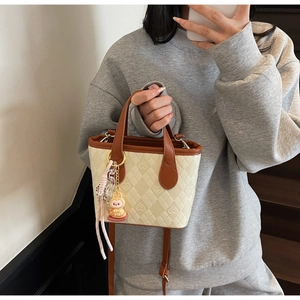 Dettaglio della borsa a tracolla beige in PU con goffratura a cuore e ciondolo a coniglio
