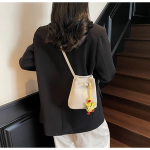 Detailed shot of white lychee grain bucket bag with cute yellow duck charm on model