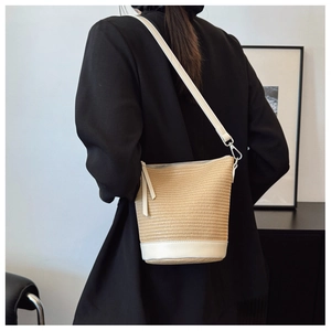 Detail view of woven straw bucket bag with white leather trim and strap for summer