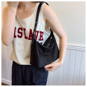 Close-up of black crescent nylon tote bag showing adjustable leather strap on model