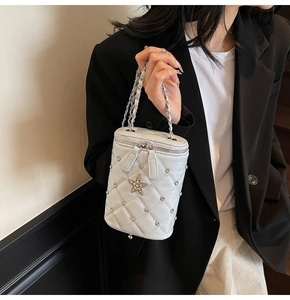 Détail du sac seau matelassé avec étoile et bandoulière chaîne porté par un mannequin