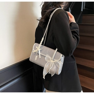 Close-up of wood-texture shoulder bag with delicate white mesh bow detail