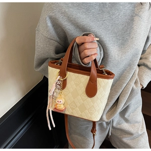 Dettaglio della mini borsa a secchiello con motivi geometrici e ciondolo a coniglio rosa